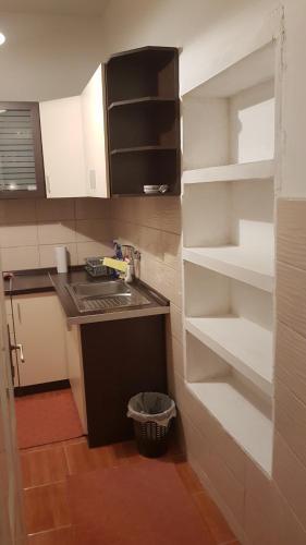 a kitchen with white shelves and a sink at AMY APARTMAN in Tuzla