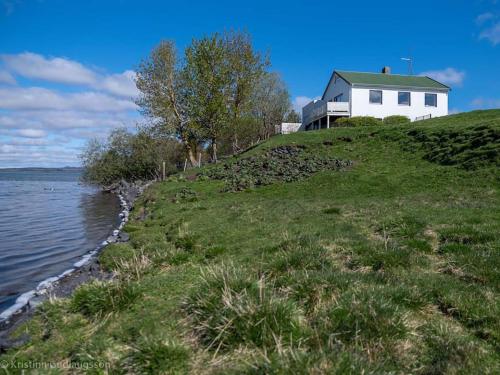 une maison blanche au sommet d'une colline près de l'eau dans l'établissement Myvo The House Geiteyjarströnd 4, à Geiteyjarstrond