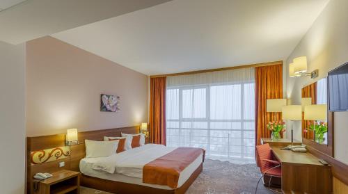 Pokój hotelowy z łóżkiem, biurkiem i oknem w obiekcie RIN Airport Hotel w mieście Otopeni