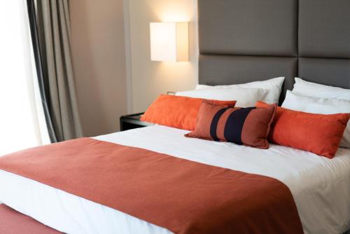 1 dormitorio con 1 cama grande con almohadas de color naranja en Carles Hotel en Buenos Aires