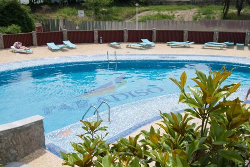 ein großer Pool mit einer Frau, die auf Liegestühlen daneben sitzt in der Unterkunft Hotel Paradiso in Mangalia