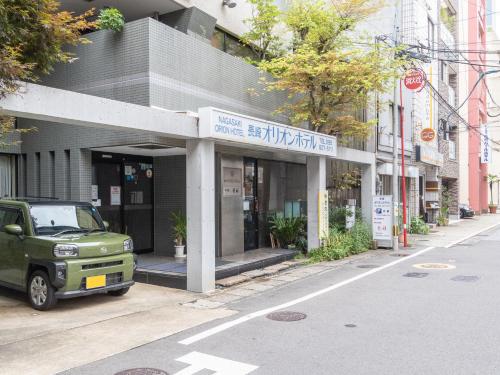 un camion verde parcheggiato di fronte a un edificio di Nagasaki Orion Hotel a Nagasaki