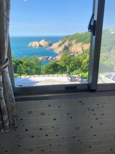 uma janela com vista para a praia e para o oceano em Home run Homestay em Dongyin/