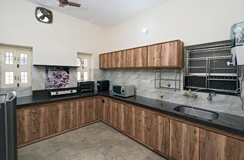 a large kitchen with wooden cabinets and a sink at Madhav's Mallet in Jaipur