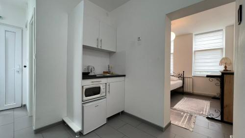 a white kitchen with a sink and a stove at Apartmani Aurora in Tuzla