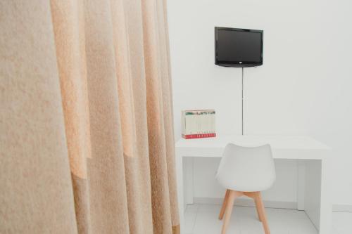 a room with a curtain and a tv and a chair at Hotel Olive in Osuna