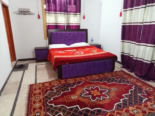 a bedroom with a bed and a red rug at Hotel Grand Home in Murree