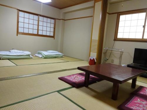 Habitación con mesa y habitación con cama en Imazato Ryokan, en Osaka