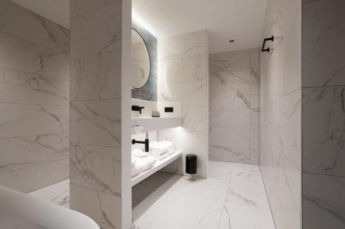 bagno bianco con lavandino e specchio di Van der Valk TheaterHotel De Oranjerie a Roermond