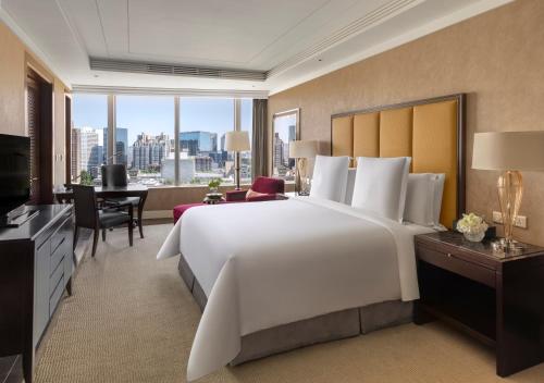 ein großes Schlafzimmer mit einem großen weißen Bett und einem Schreibtisch in der Unterkunft Four Seasons Hotel Beijing in Peking