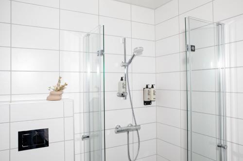 a shower in a bathroom with white tiles at Bob W Sentralen in Oslo