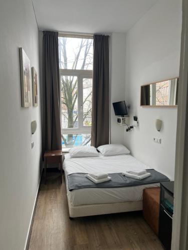 ein Schlafzimmer mit einem Bett und einem großen Fenster in der Unterkunft MAX Hotel Amsterdam in Amsterdam