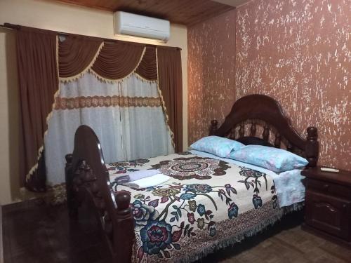 a bedroom with a bed with a flowered blanket and a window at Salto dos hermanas in Puerto Iguazú