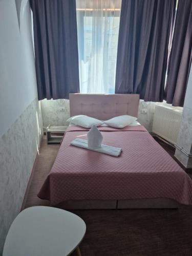 a bedroom with a pink bed with a napkin on it at Hotel Minion in Constanţa