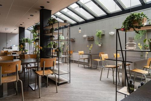 un ristorante con tavoli, sedie e piante di Hotel de Duif Lisse - Schiphol a Lisse