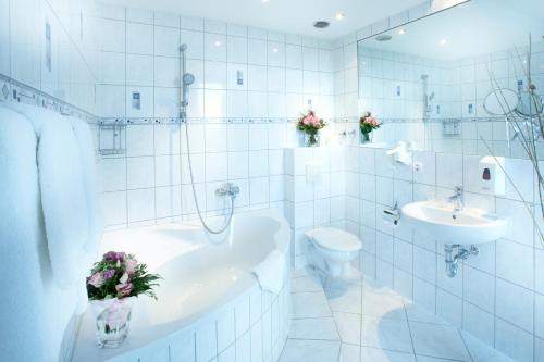 a white bathroom with a tub and a toilet and a sink at Hotel Astor Kiel by Campanile in Kiel