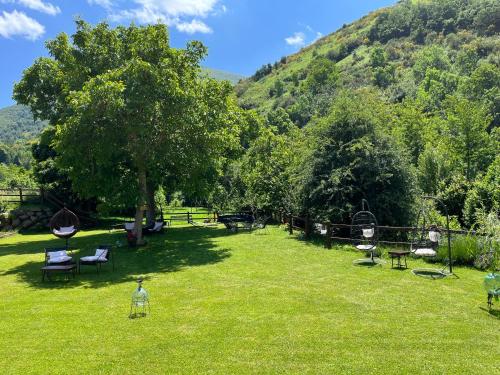 un parque con sillas, un árbol y montañas en Hotel Eigón, en Posada de Valdeón