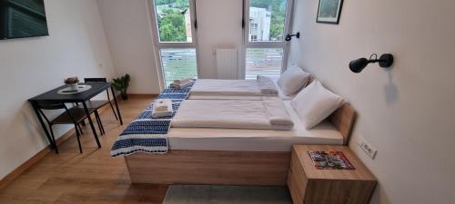 a bedroom with two beds and a table and a window at Pansion Hukić B&B in Tuzla