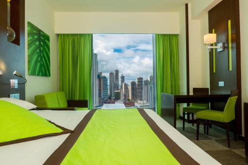 una camera con letto verde, scrivania e finestra di Riu Plaza Panamá a Città di Panama