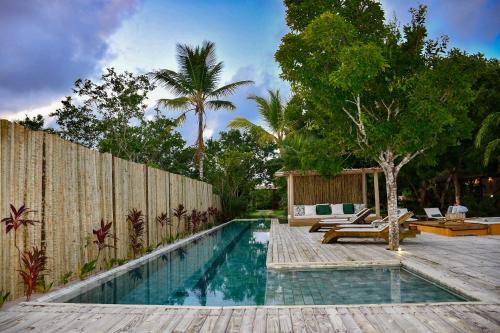 una piscina en un patio trasero con una valla de madera en Riviera Trancoso en Trancoso