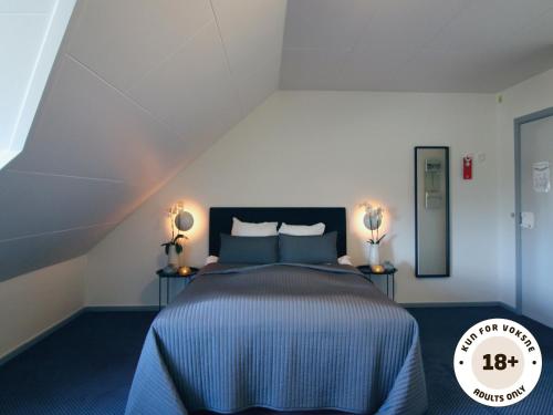 - une chambre avec un lit avec des draps bleus et deux lampes dans l'établissement Ærø Hotel - Adults only, à Marstal