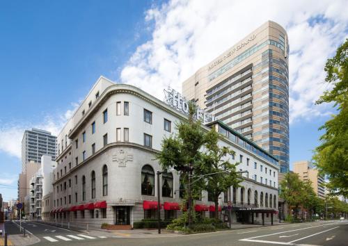 a white building on a city street with tall buildings at Hotel New Grand in Yokohama