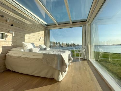 een slaapkamer met een groot bed en een groot raam bij Seaside Glass Villas in Kemi