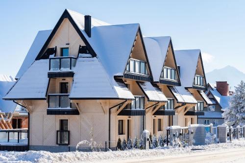 una casa con la neve sul tetto di Alpina Residence & Kameralne SPA a Bukowina Tatrzańska