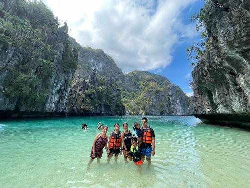 un groupe de personnes debout dans l'eau sur une plage dans l'établissement Hidden of Cailan Extension Transient House, à El Nido