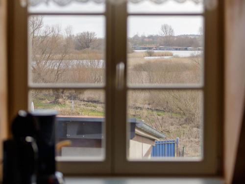 ein Fenster mit Blick auf ein durch es hindurchgesehenes Feld in der Unterkunft Fachwerk App 2 2 OG in Röbel