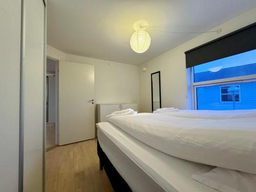 een witte slaapkamer met een groot bed en een raam bij Hotel Nuka in Ilulissat