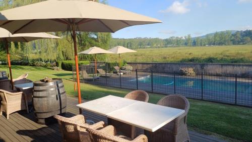 eine Terrasse mit einem Tisch, einem Sonnenschirm und einem Pool in der Unterkunft Bosch Hoek Golf & Lodge in Balgowan