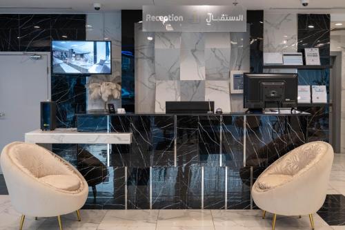 a lobby with two chairs and a desk and a television at Abela Al Hamra - Palestine Street in Jeddah