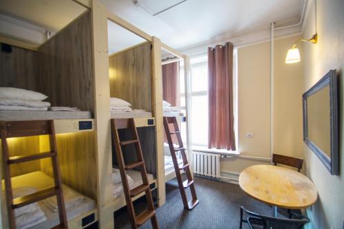 a room with bunk beds and a table and a desk at Imaginary Hostel in Tallinn