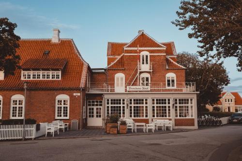 een groot bakstenen gebouw met witte tafels en stoelen bij Brøndums Hotel in Skagen