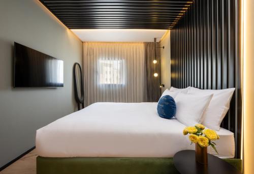 a bedroom with a large white bed and a table at Hotel Poli Urban By AFI Hotels in Tel Aviv