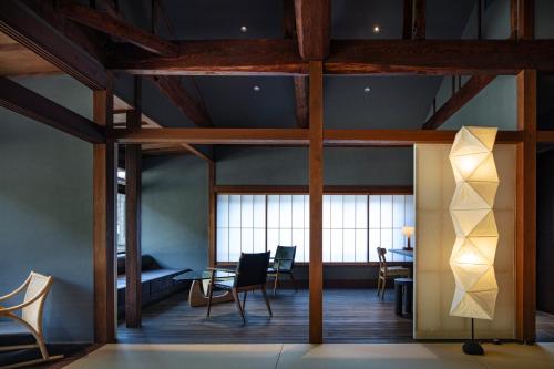 une chambre avec des chaises, une table et des fenêtres dans l'établissement Kobayashiya -Kinosaki Onsen-, à Toyooka