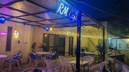 un restaurant avec des tables et des chaises ainsi qu'un panneau indiquant le café de l'établissement dans l'établissement R.M RESIDENCY, à Lahore