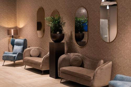 a waiting room with two chairs and two mirrors at Hotel Gerardus in Szeged