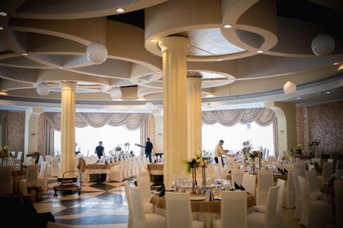 - une salle de banquet avec des tables et des chaises blanches dans l'établissement Black Tulip Hotel, à Dej