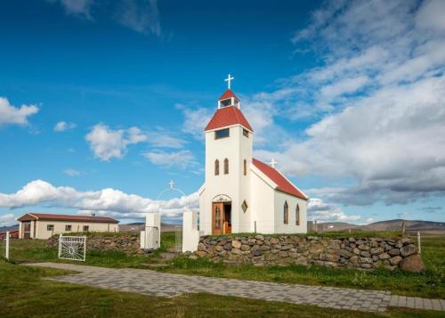 una iglesia blanca con techo rojo y pared de piedra en Fjalladýrð Hotel en Modrudalur