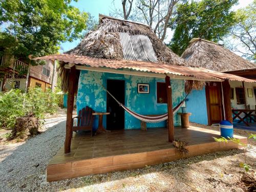 a small blue house with a thatched roof at Hotel Mon Ami in El Remate