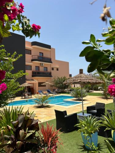 a resort with a pool and chairs and a building at Zarafah in Poponguine