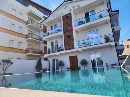 un hotel con piscina frente a un edificio en Hotel Villa ATA en Durrës