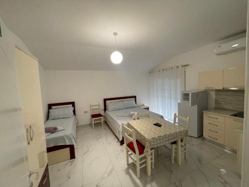 um quarto com duas camas e uma mesa e uma cozinha em Vila Ornela em Shëngjin