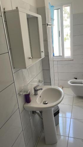 a white bathroom with a sink and a toilet at Vila Ornela in Shëngjin