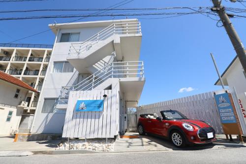 une voiture rouge garée devant un bâtiment dans l'établissement パークサイドモリ, à Motobu