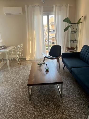 Sala de estar con sofá azul y mesa de centro en MZ apartment, en Nea Peramos