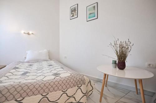 a white bedroom with a bed and a table at Vista Apartment in Opatija