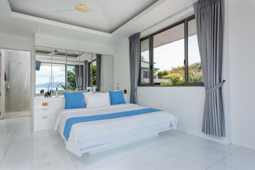 um quarto branco com uma cama grande e almofadas azuis em Villa Oceane em Thong Son Beach